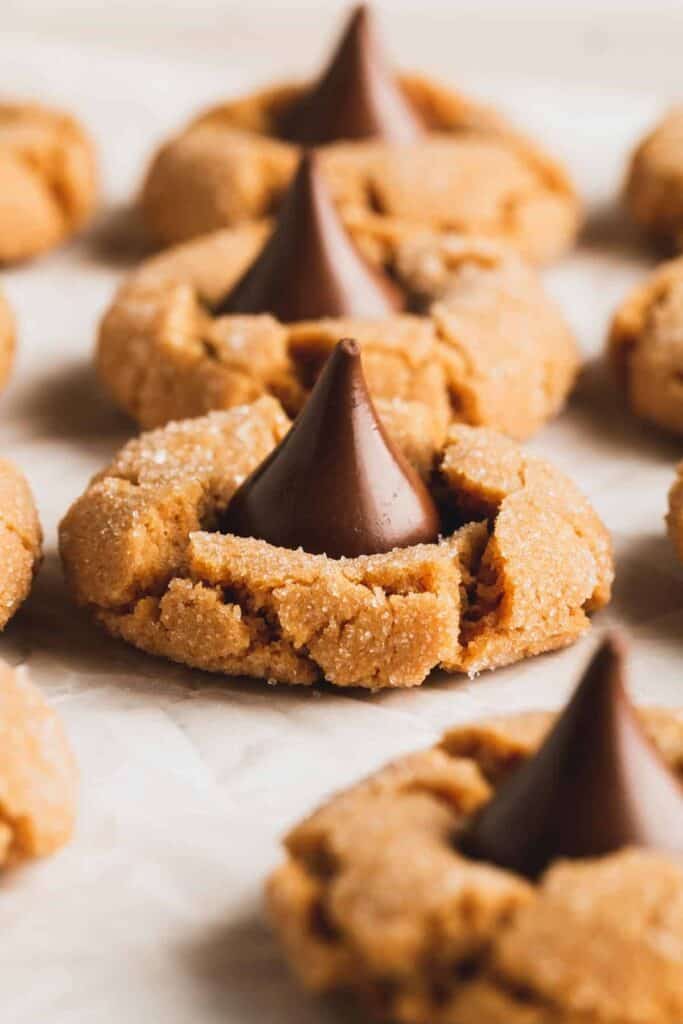 Gluten-free peanut butter blossom cookies scattered on crinkled parchment paper.