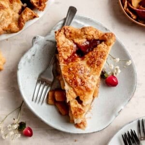 A slice of gluten free apple pie with lettice top on small apple shaped plate.