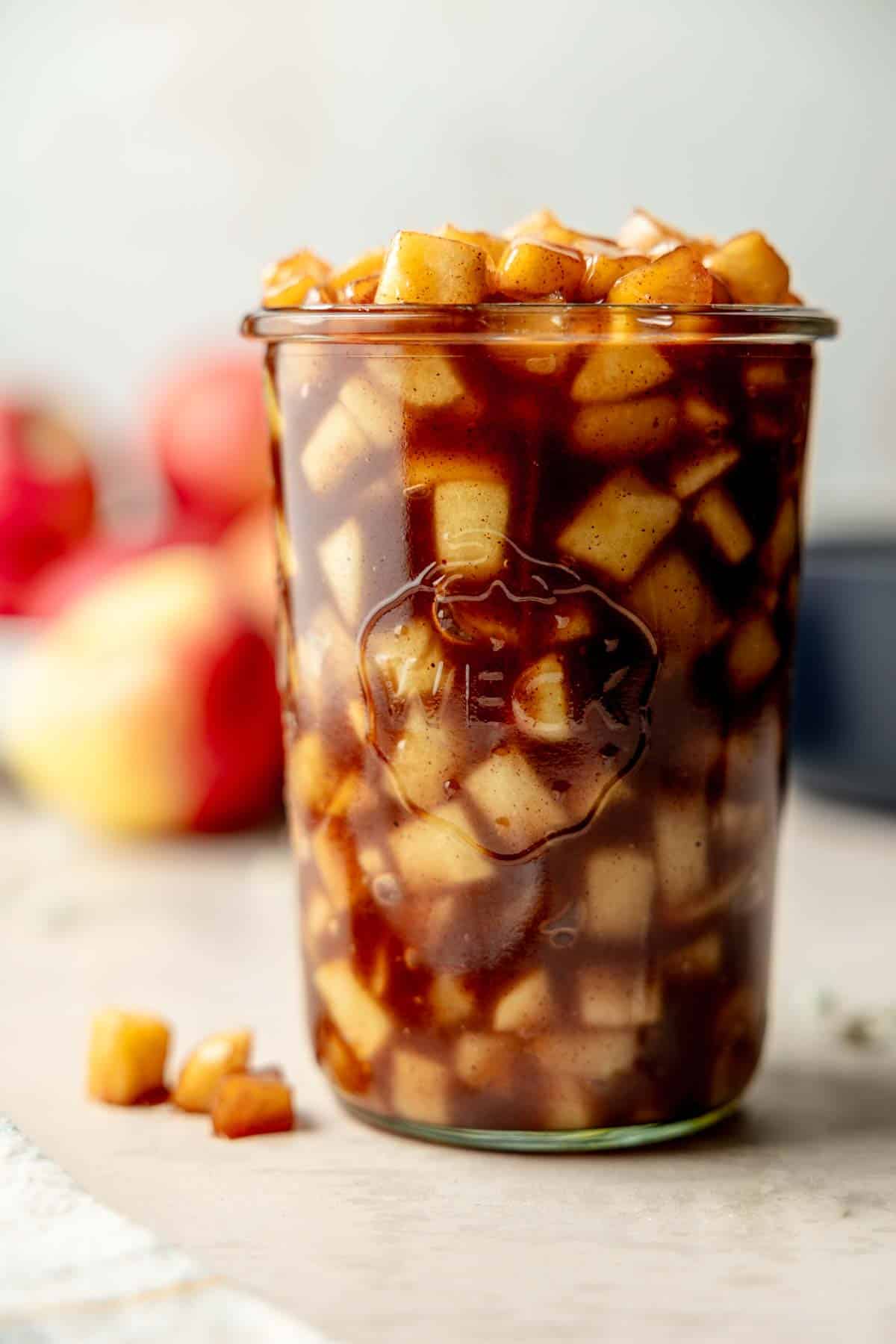 A weck jar filled with homemade apple pie filling consisting of diced apples and brown sauce.