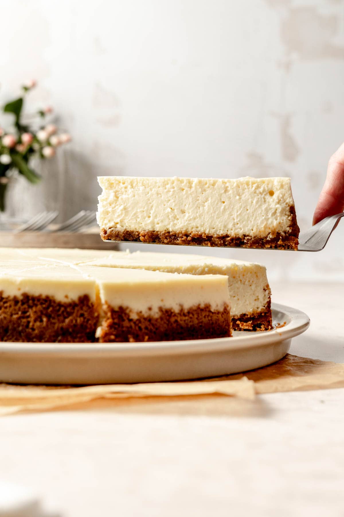 A slice of gluten-free cheesecake lifted from the plate on serving spatula.