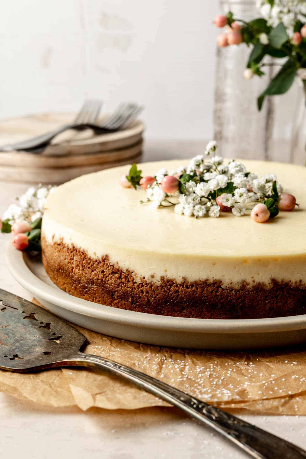 A gluten-free cheesecake with graham cracker crust, garnished with flowers.