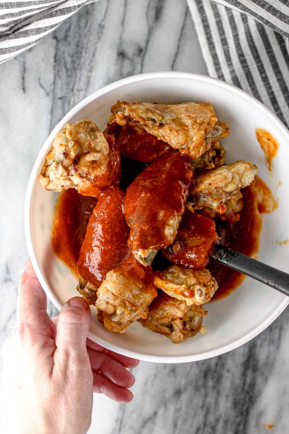 Dousing chicken wings in sauce.