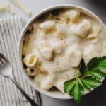 A bowl of gluten-free macaroni and cheese garnished with fresh parsley.