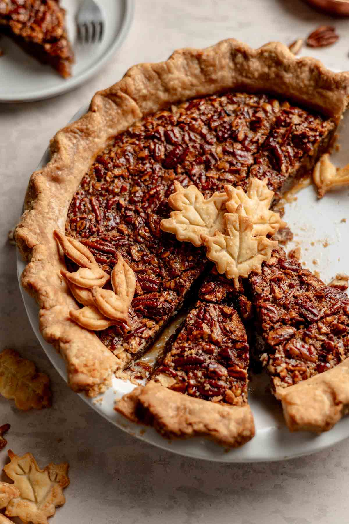 Gluten-Free Pecan Pie sliced in a white pie pan topped with leaf shaped pie cutouts.