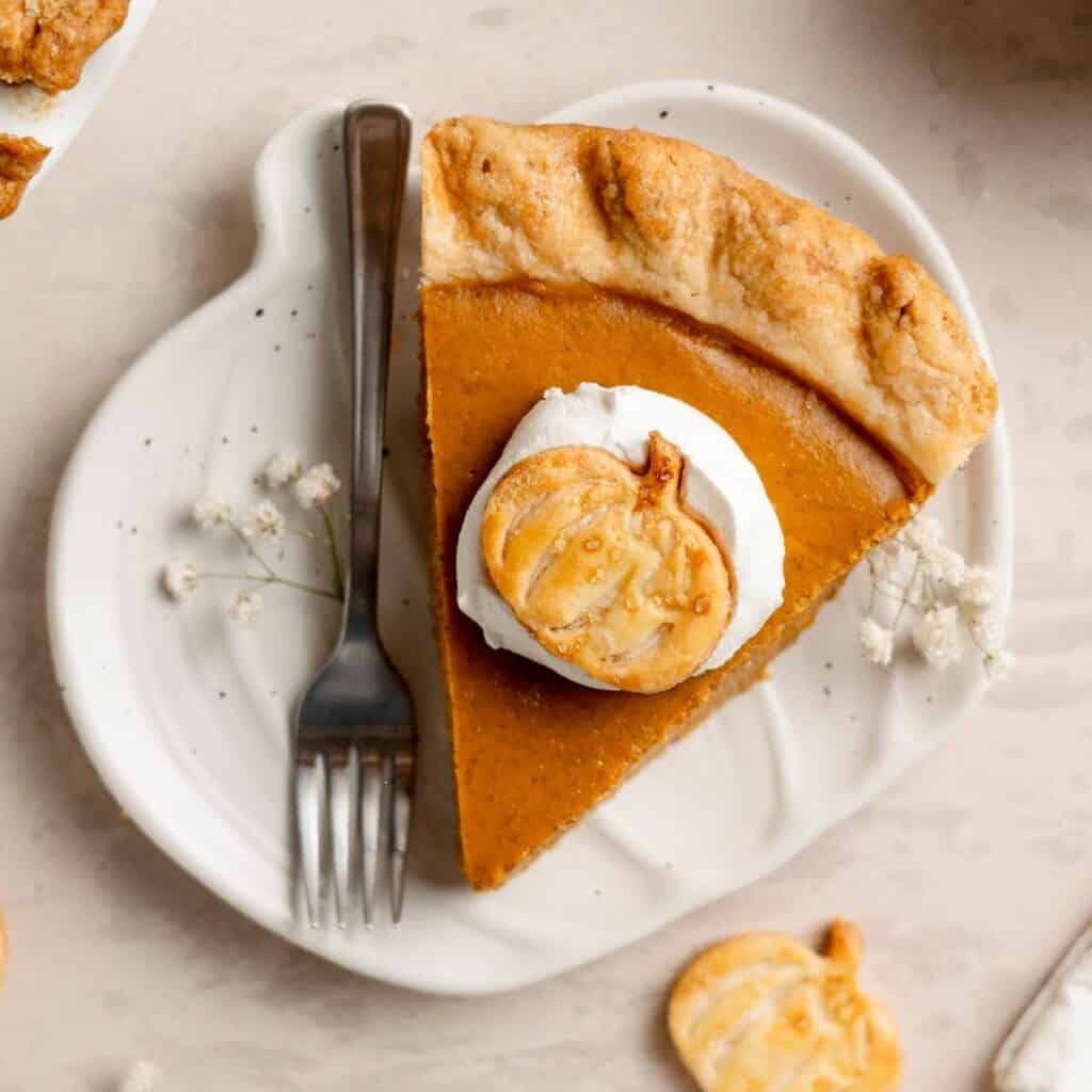 A slice of gluten free pumpkin pie on a small pumpkin shaped plate.