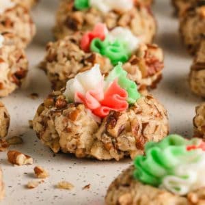 A closeup view of a pecan thumbprint with red, white, and green buttercream frosting.