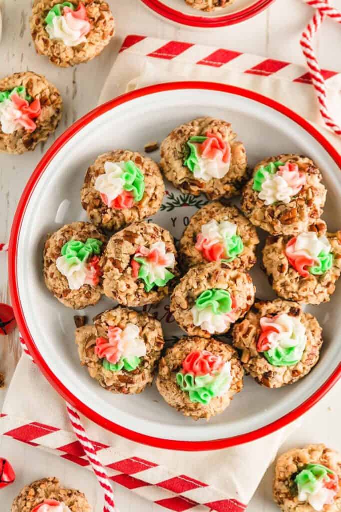 A red enaelware plate with a pile of thumbprint cookies.