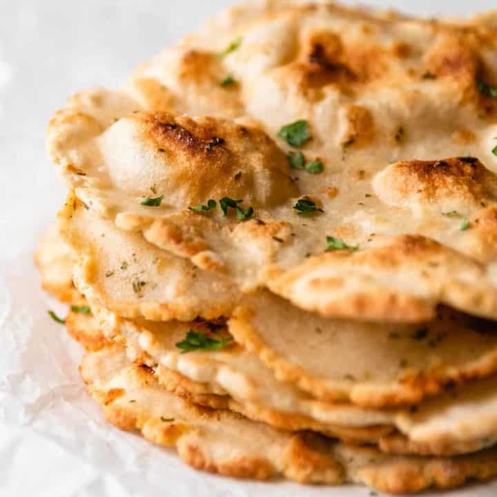 A stack of 3 ingredient gluten-free flatbread with parsley on top.