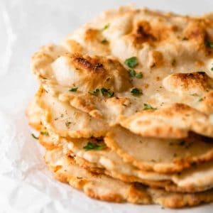 A stack of 3 ingredient gluten-free flatbread with parsley on top.