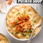 A bowl of creamy gluten-free potato soup topped with bacon, white cheddar cheese, and chives.