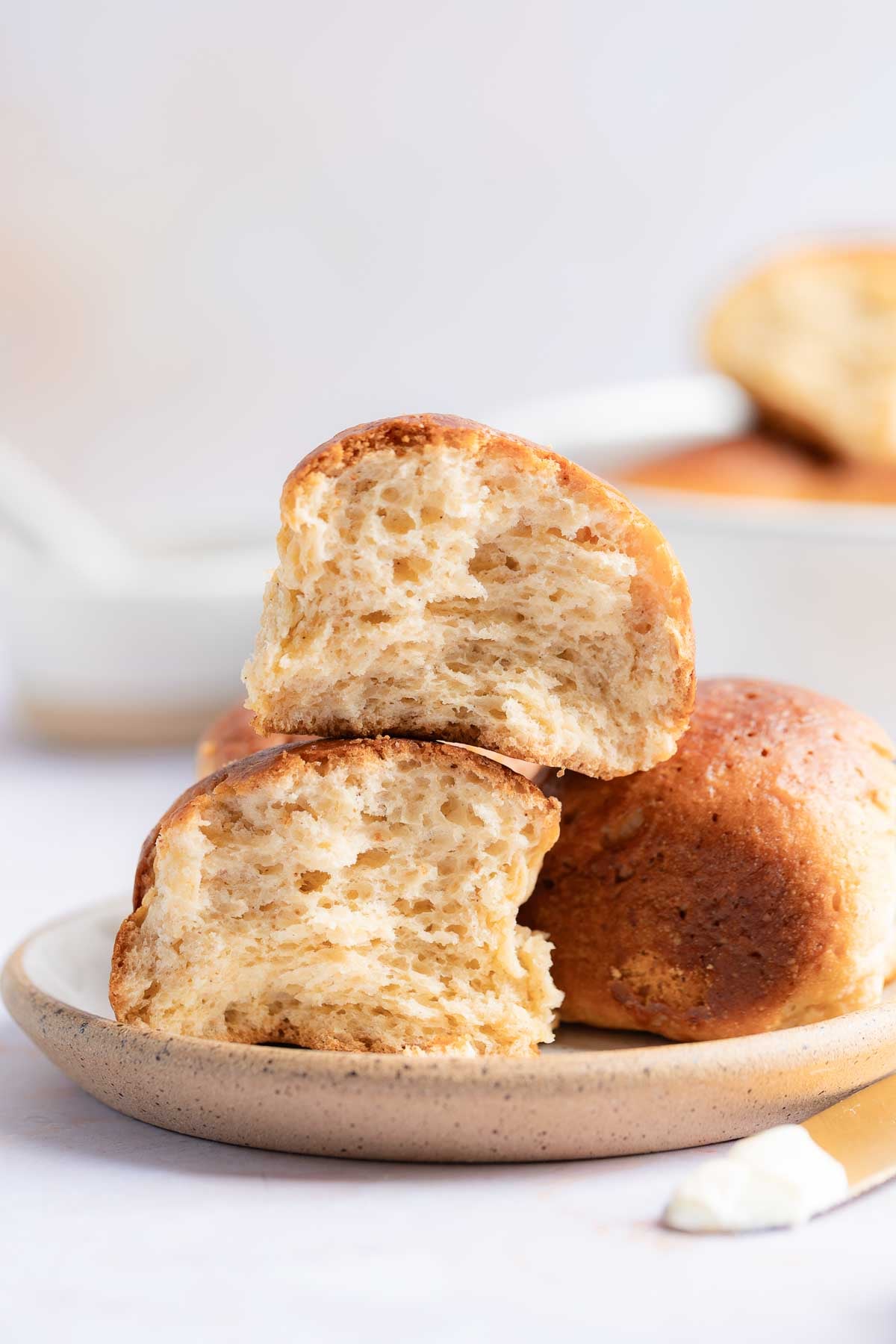Gluten-Free Hawaiian Rolls on plate, one split apart to show fluffy interior texture.