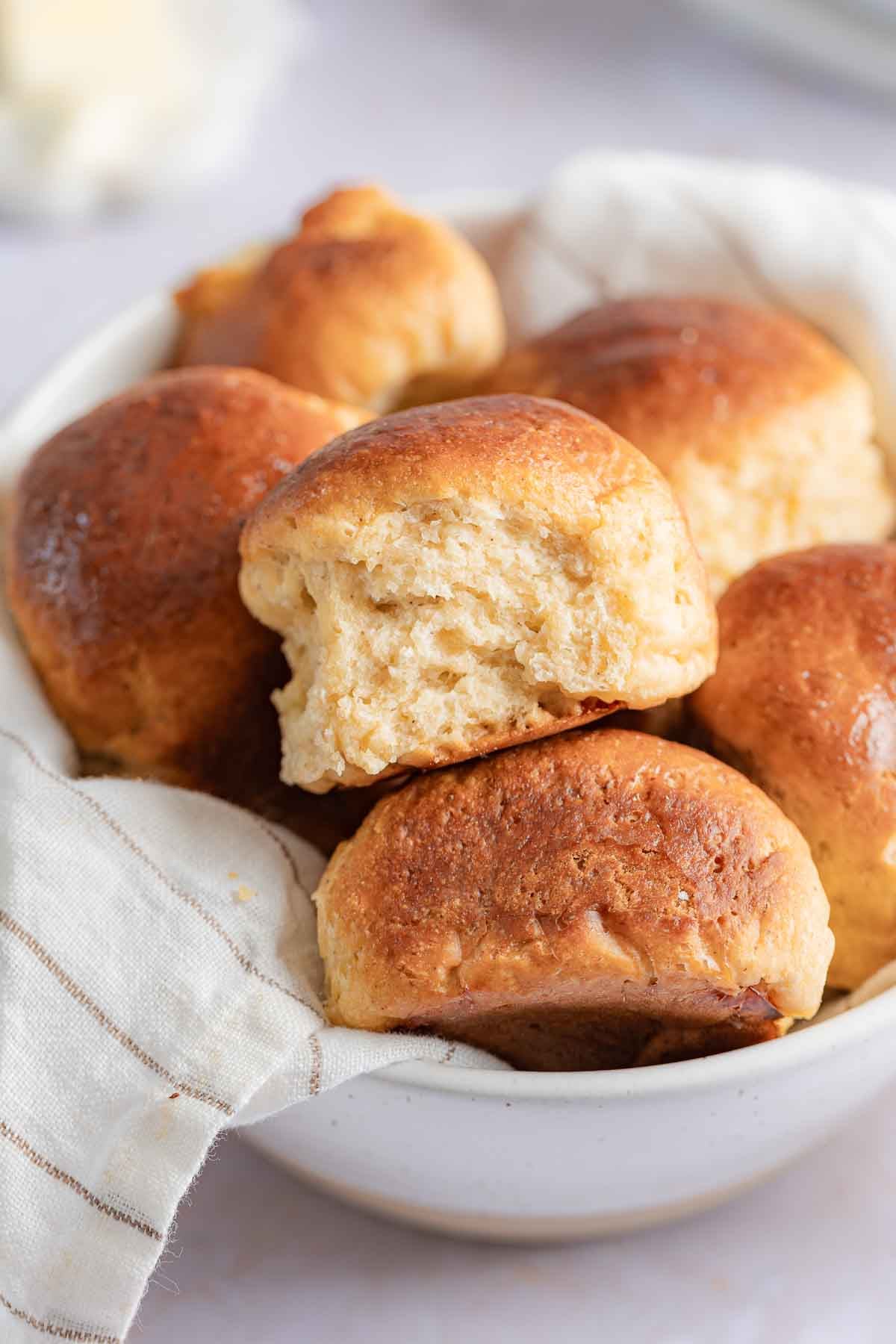 Gluten-Free Hawaiian Rolls stacked in a bowl with a linen towel.