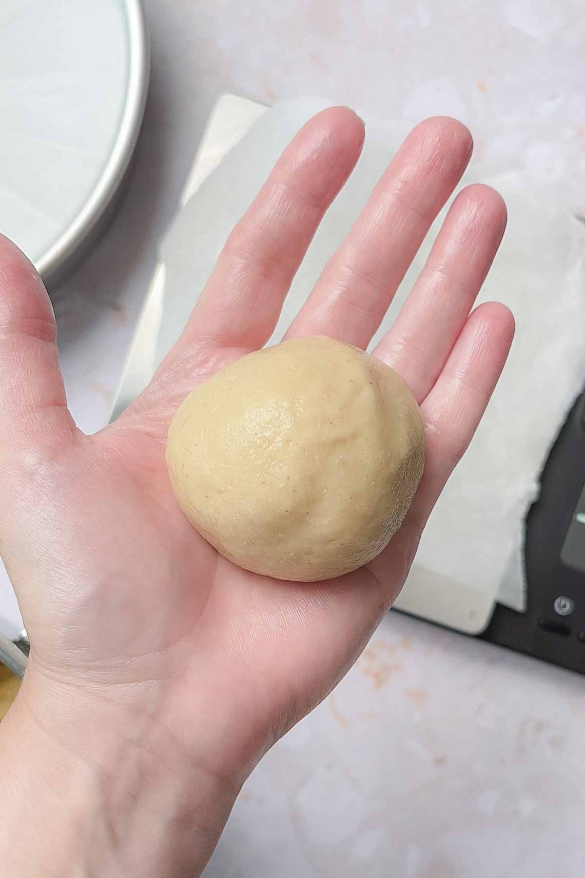 Portion of dough rolled into smooth ball in greased hand.