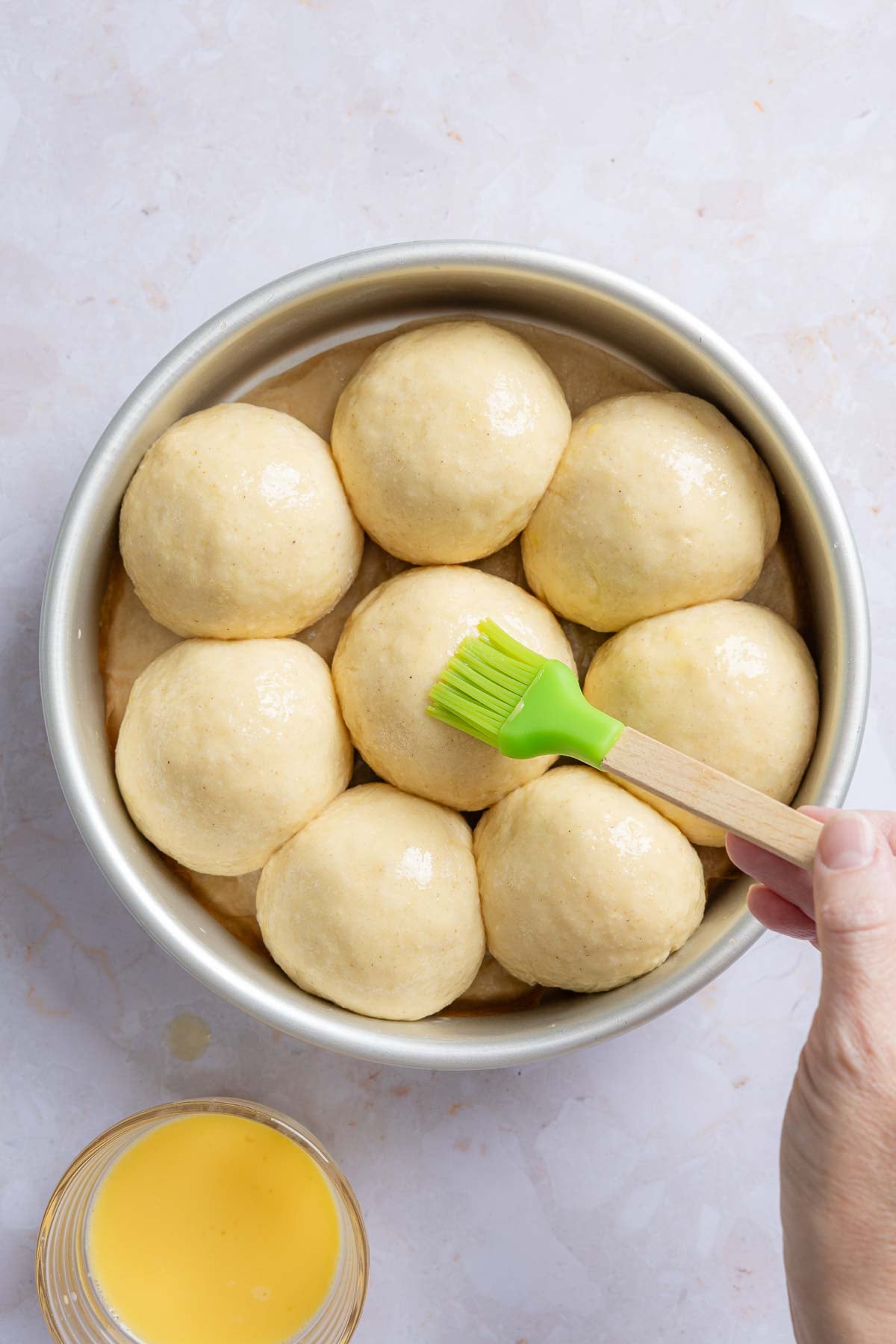 Dough balls in pan after rising, brushed with melted butter.