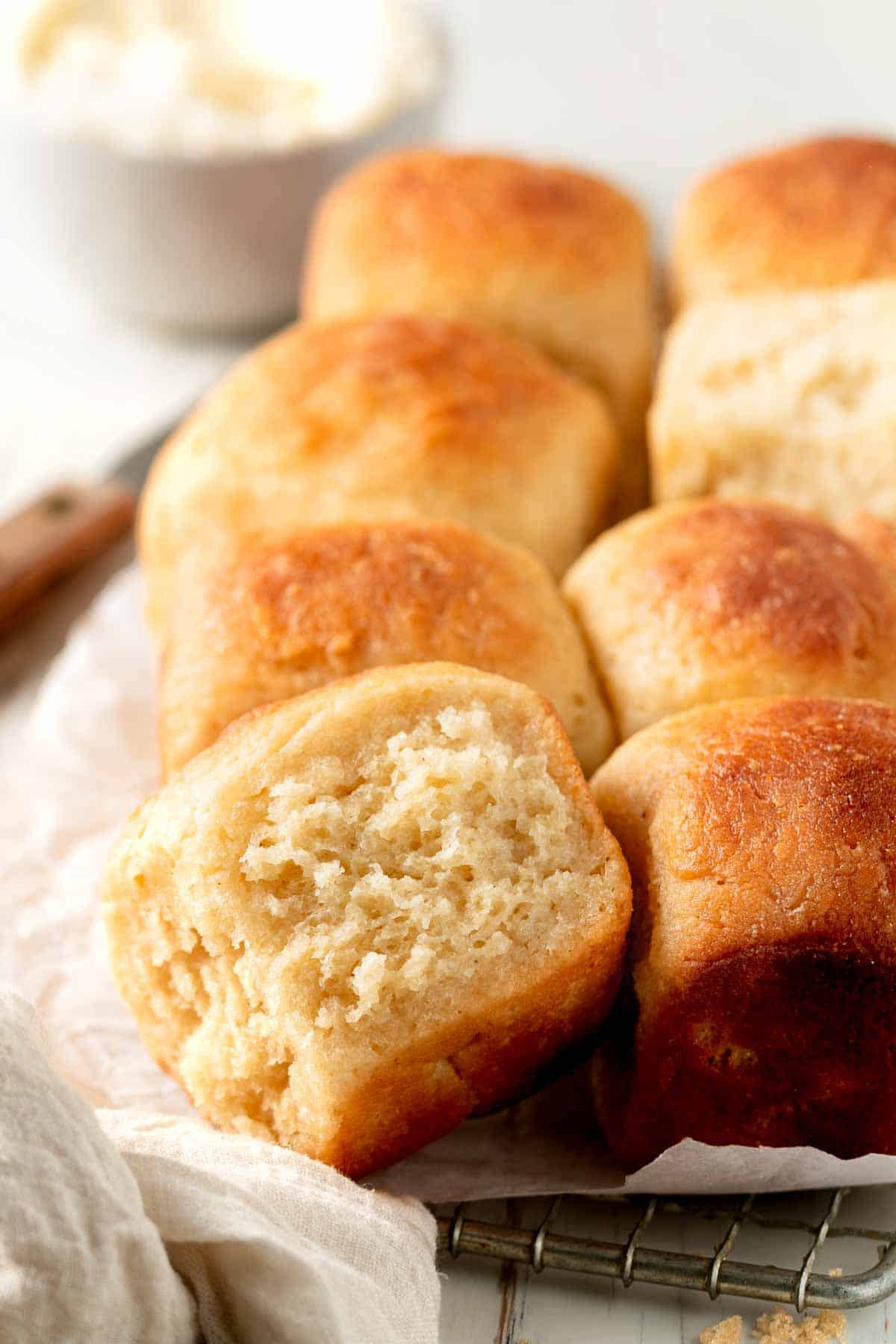 Gluten-free Hawaiian Rolls on a piece parchment paper, on a wire rack.