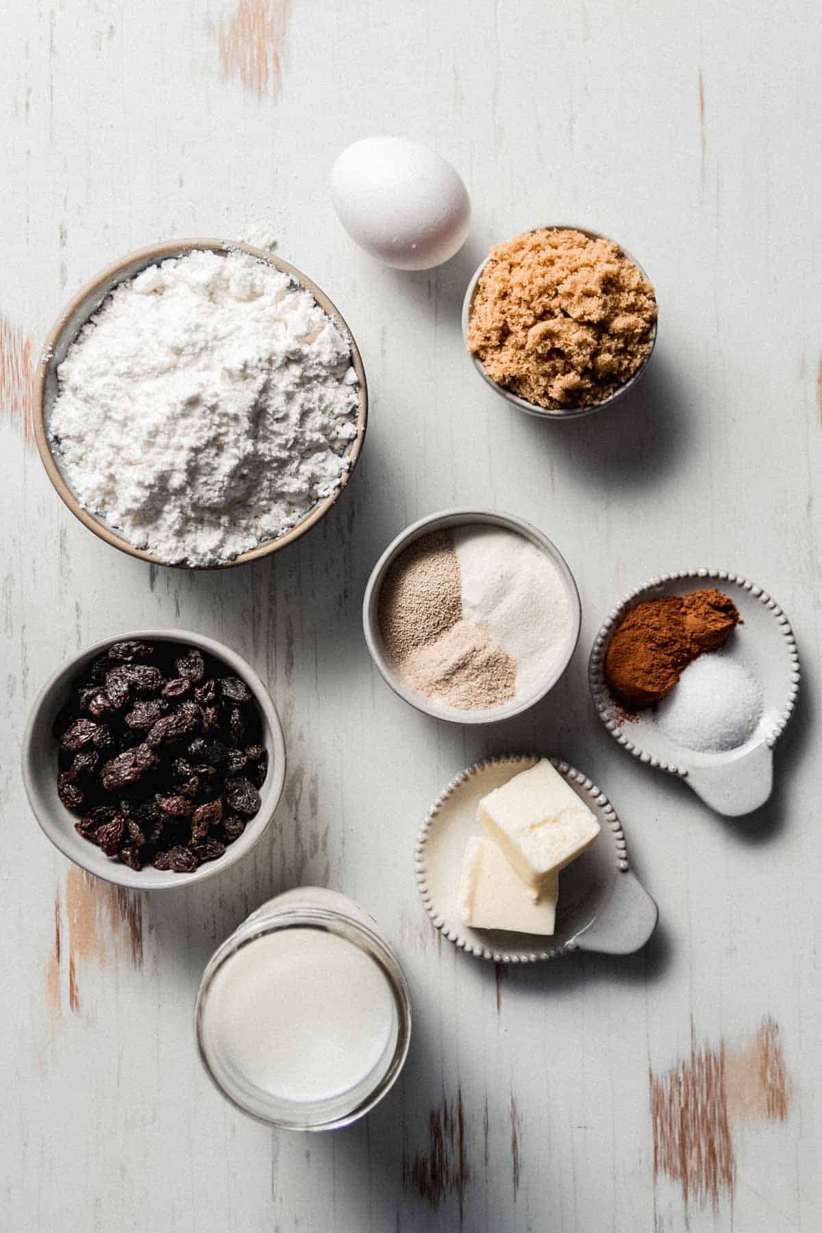Ingredients measured in bowls including gluten-free flour, raisins, butter, sugar, egg, and spices.