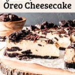 Gluten Free Oreo Cheesecake on a rustic wooden cake stand, sliced to show interior filled with cookies and cream.