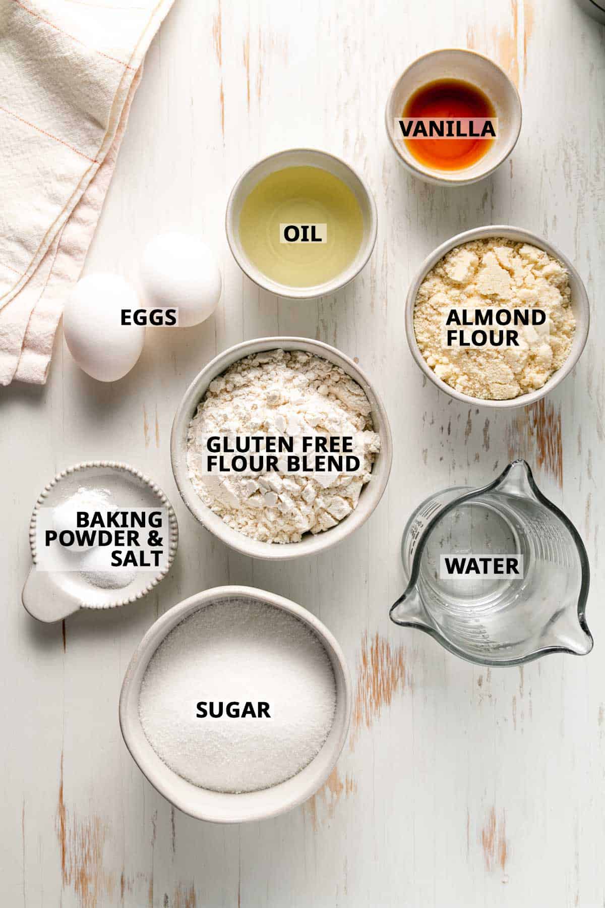 Ingredients measured in bowls on a white wooden surface.