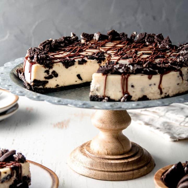 Gluten free Oreo cheesecake on a rustic cake stand.