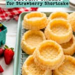 Gluten-free dessert shells for strawberry shortcakes piled on a green baking pan.