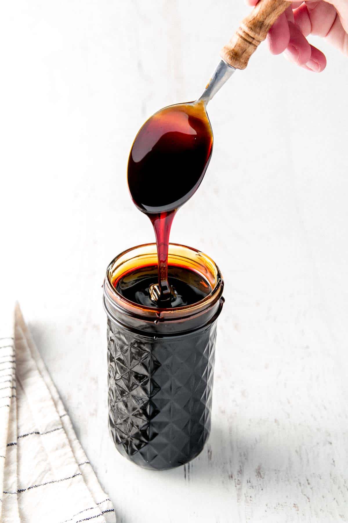Molasses dripping from spoon into a quilted mason jar.