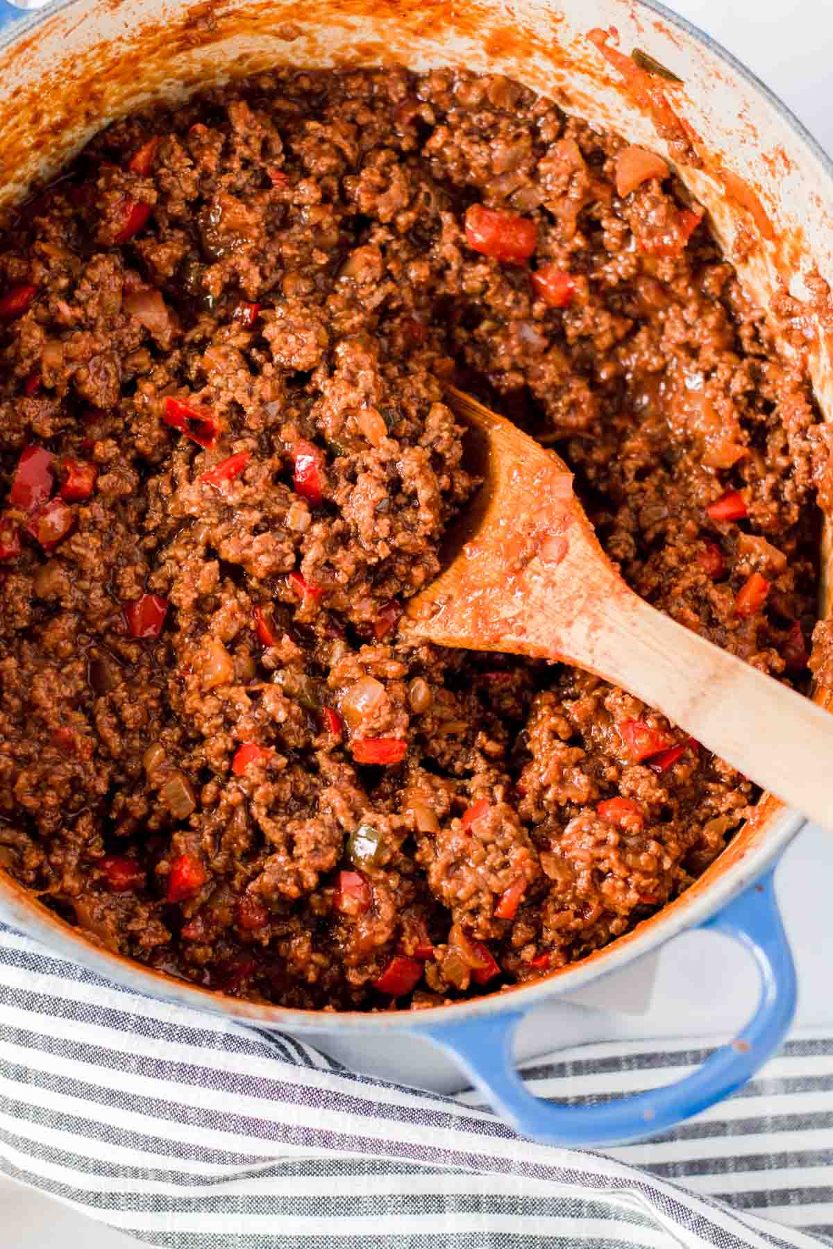 A large pot of sloppy joes with wooden spoon.