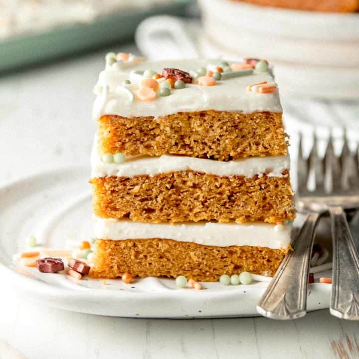 A stack of three gluten-free pumpkin bars topped with sprinkles on a small pumpkin plate.