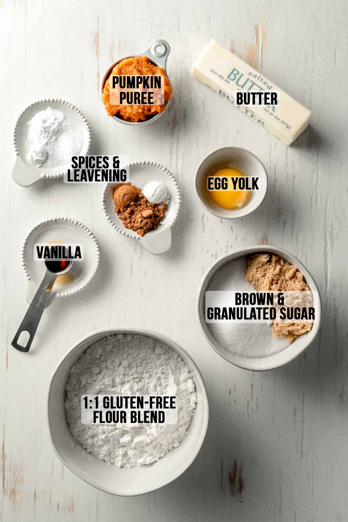 Ingredients measured in bowls on a white wooden surface.