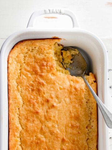 Gluten free corn casserole in white dish with scoop removed.