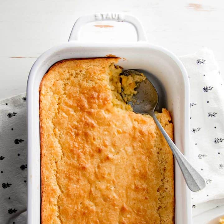 Gluten free corn casserole in white dish with scoop removed.