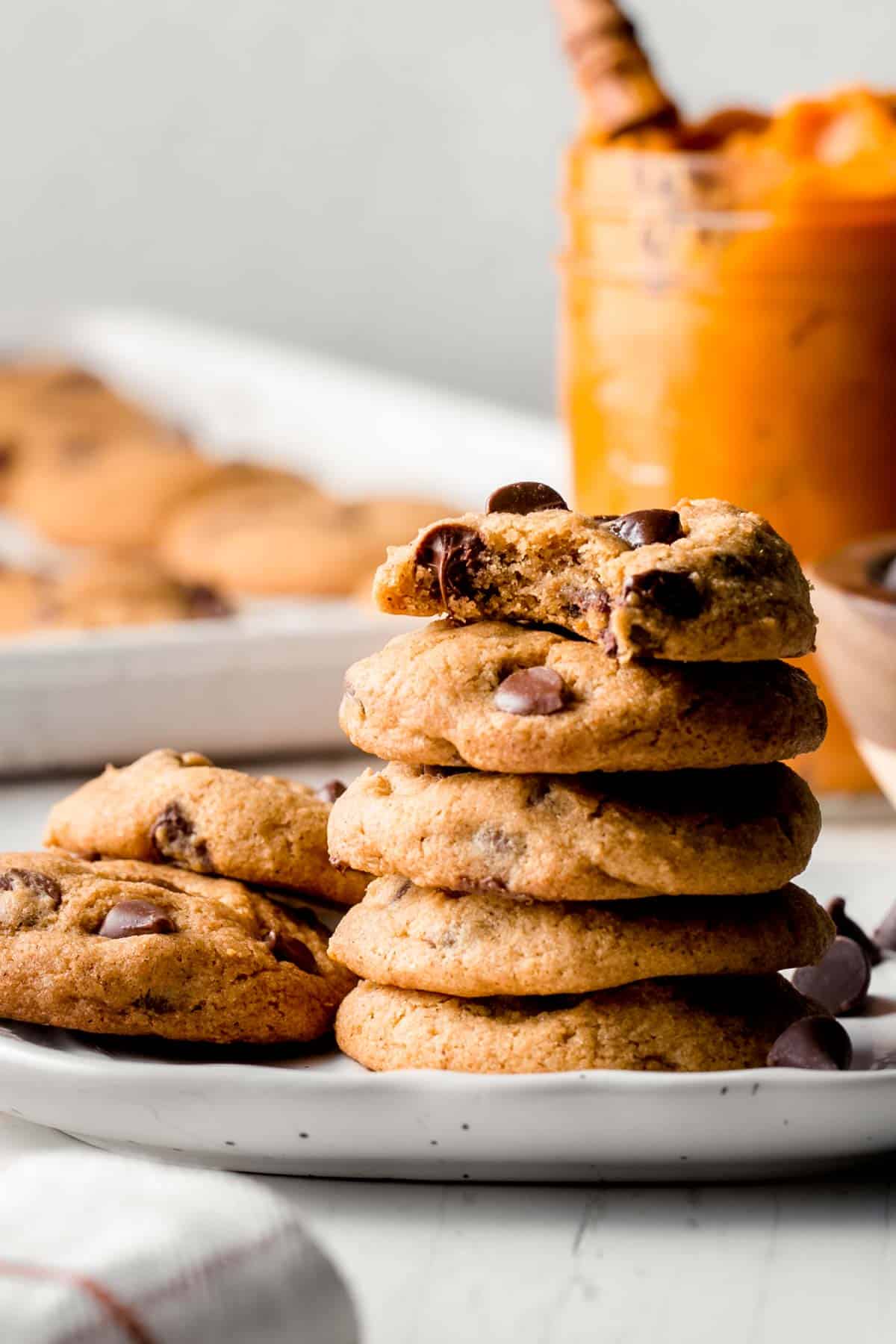 A stack of cookies on a small white pumpkin shaped plate.