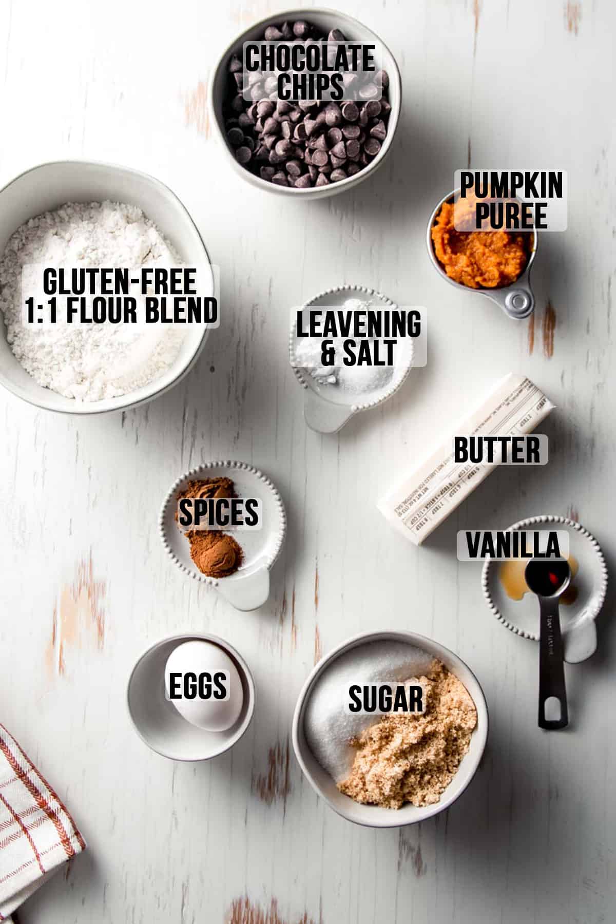 Labeled ingredients laid out in bowls on white wooden surface.