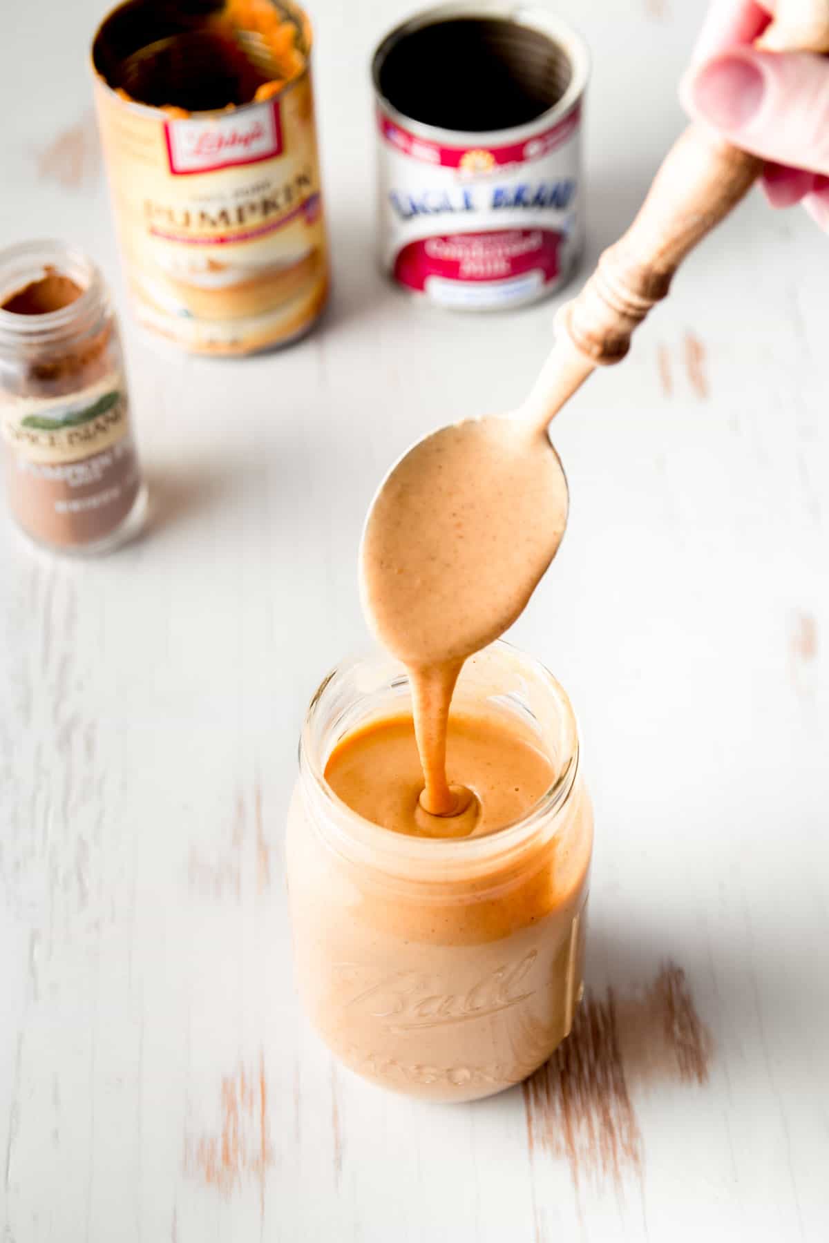 Pumpkin sauce drizzling from a spoon into a mason jar.