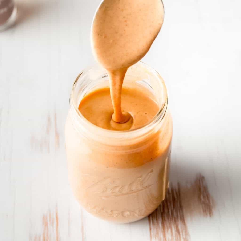 A stream of copycat Starbucks pumpkin spice sauce pouring into a mason jar.