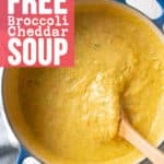 A big blue pot filled with broccoli cheddar soup stirred with wooden spoon.