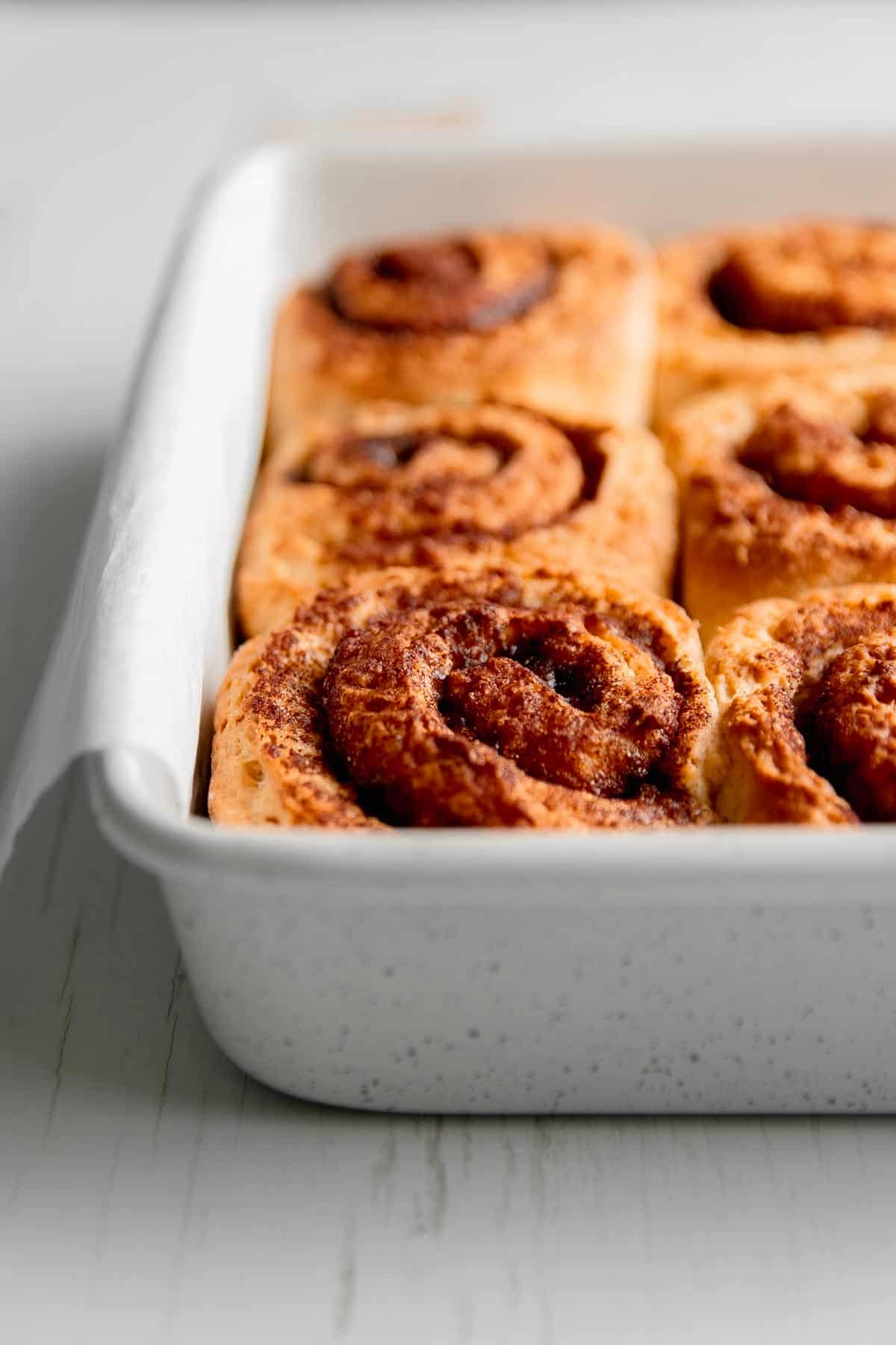 Golden brown baked rolls in a square pan.