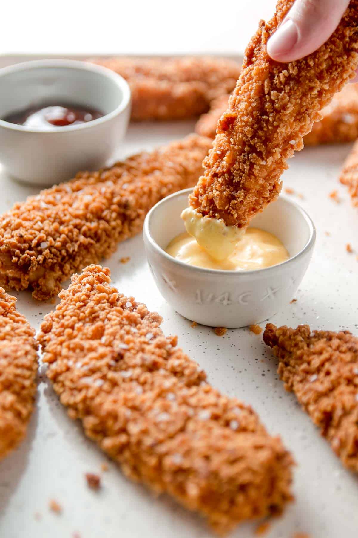 Gluten free chicken tender is dunked in honey mustard sauce.