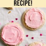 Overhead view of large gluten-free Crumbl sugar cookies topped with pink frosting, scattered with heart-shaped sprinkles on parchment paper.