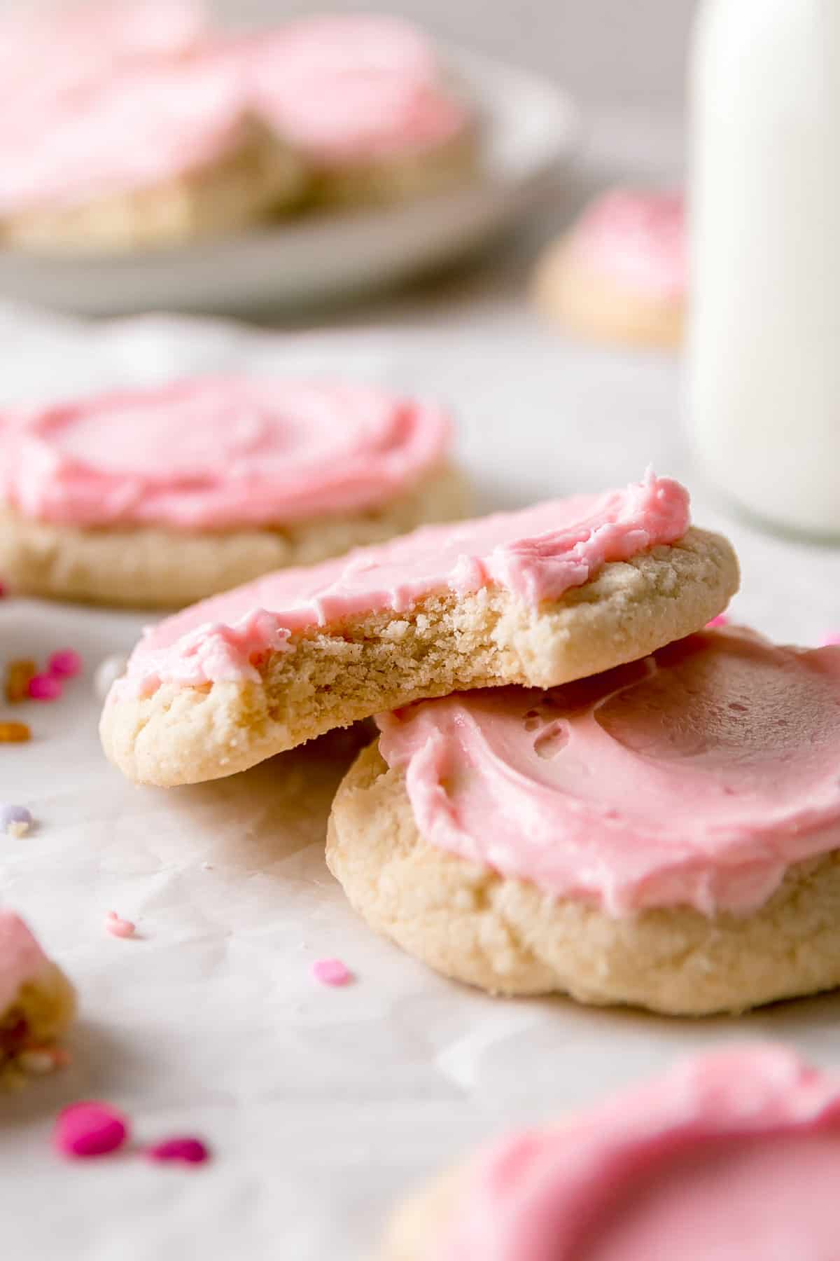 Gluten-free crumbl sugar cookie with a bite taken out resting on another cookie.