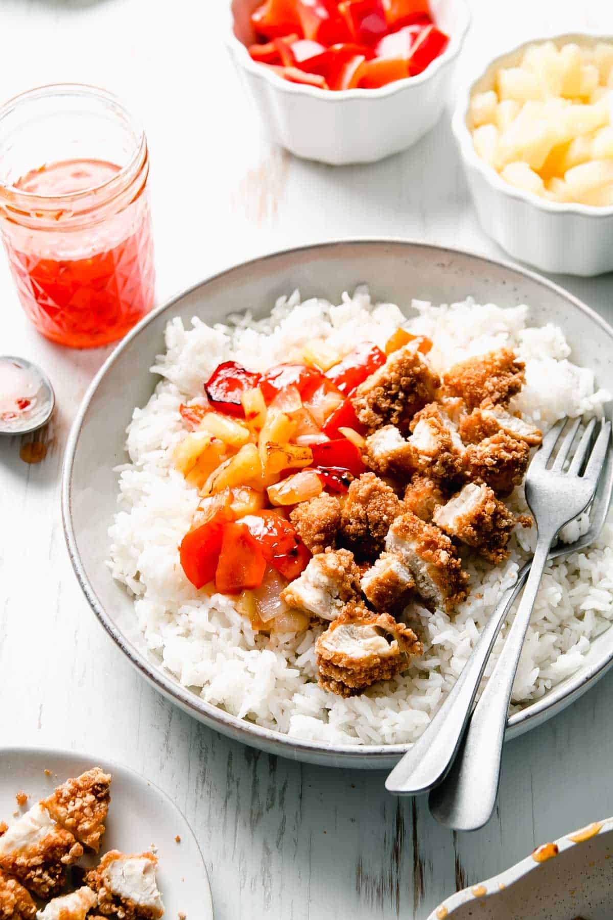 Gluten-free sweet fire chicken in a bowl over steamed rice with two forks.