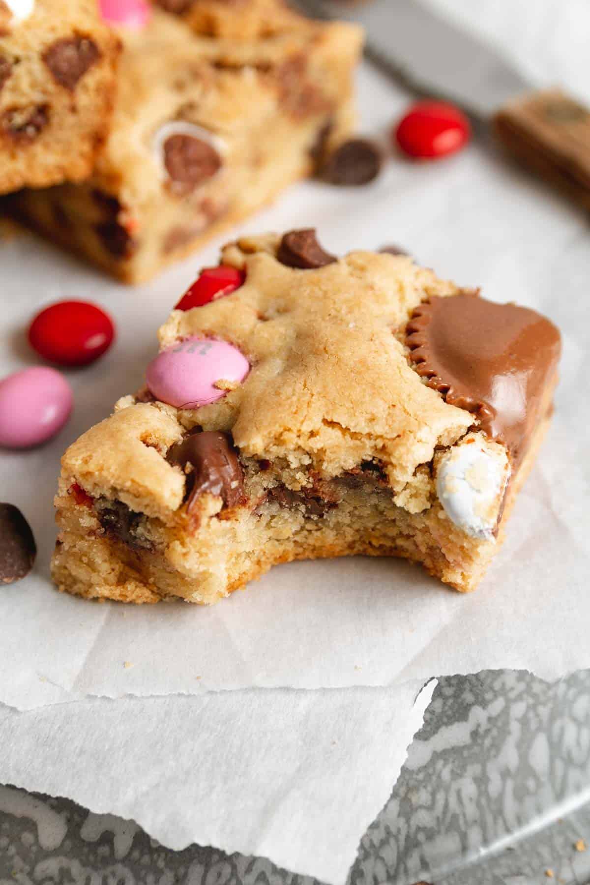 A cookie bar with a bite taken out on parchment paper. 