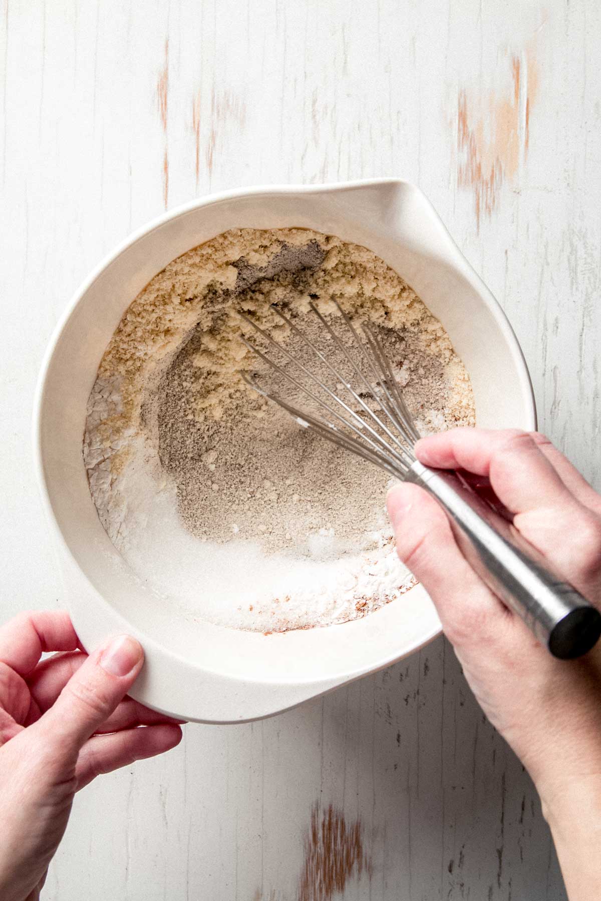 Whisking together buckwheat flour, almond flour, arrowroot, sugar, and cinnamon in a large bowl.