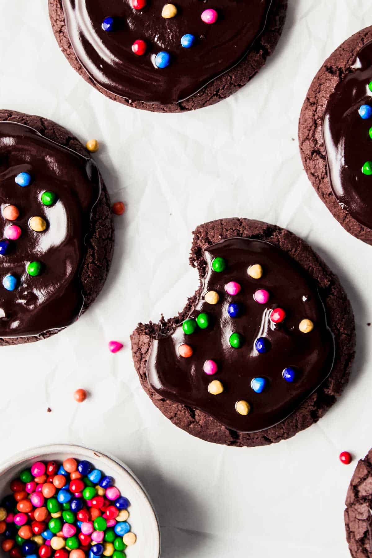 Gluten free galaxy brownie cookies with ganache and candy sprinkles, one with bite taken.