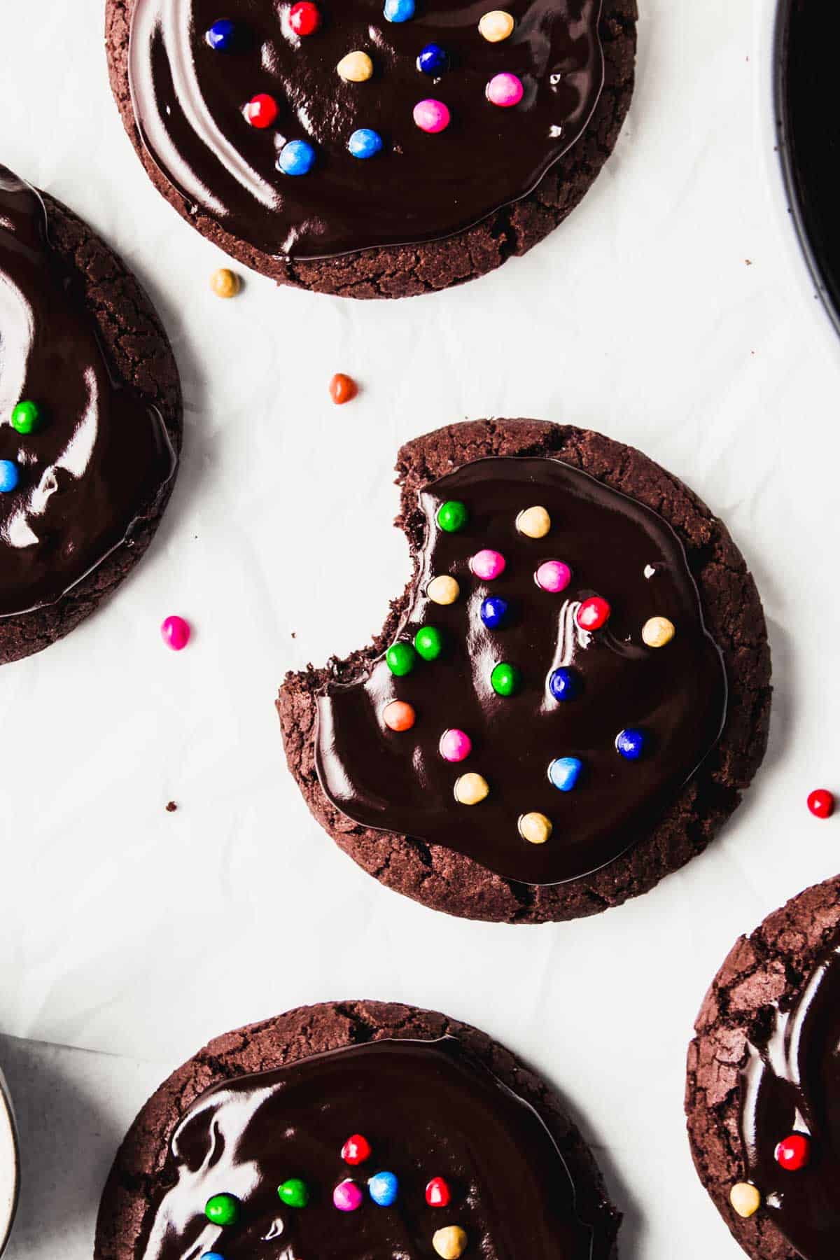 Gluten free galaxy brownie cookies with ganache and candy sprinkles, one with bite taken.