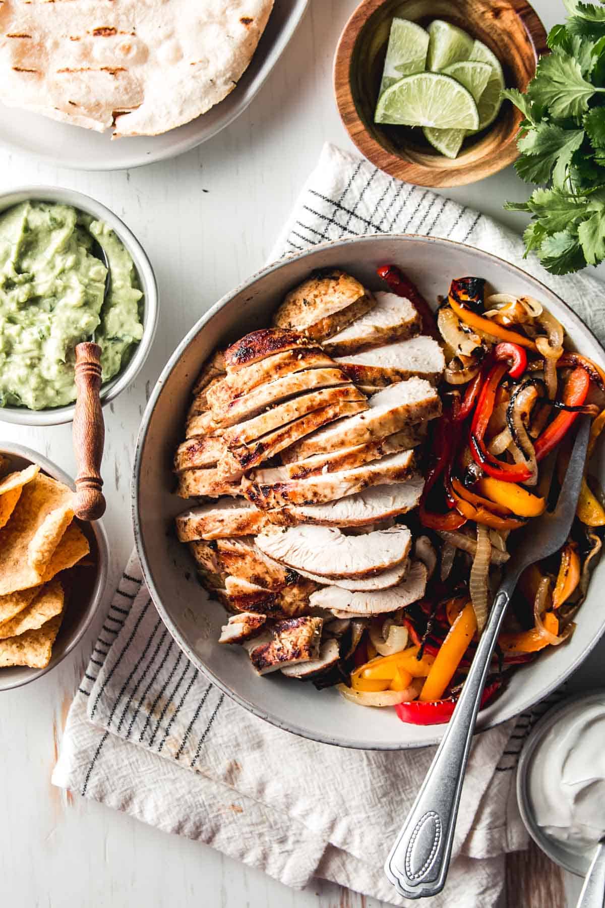 Sliced mexican citrus chicken in a bowl with fajita peppers and onions.