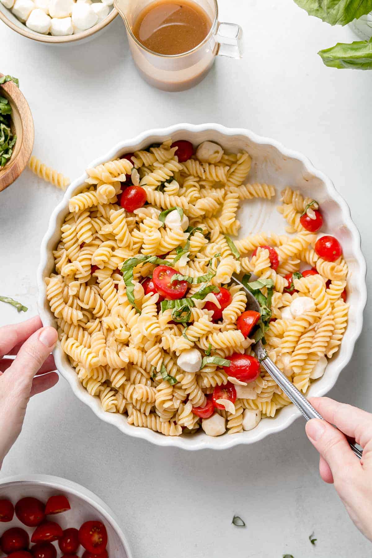 Stirring pasta salad ingredients together in serving dish.