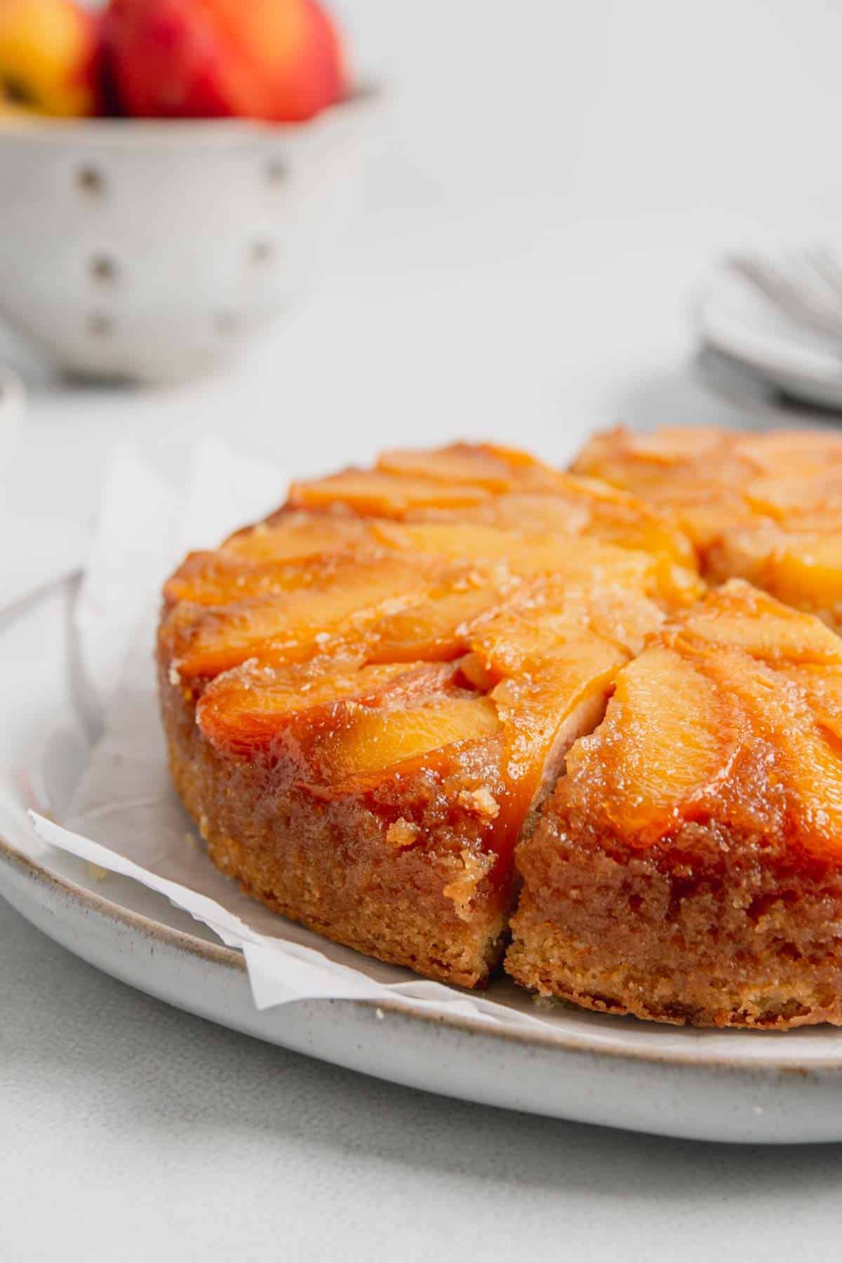 Side view of baked gluten-free peach cake with golden brown edges and gooey peaches on top.