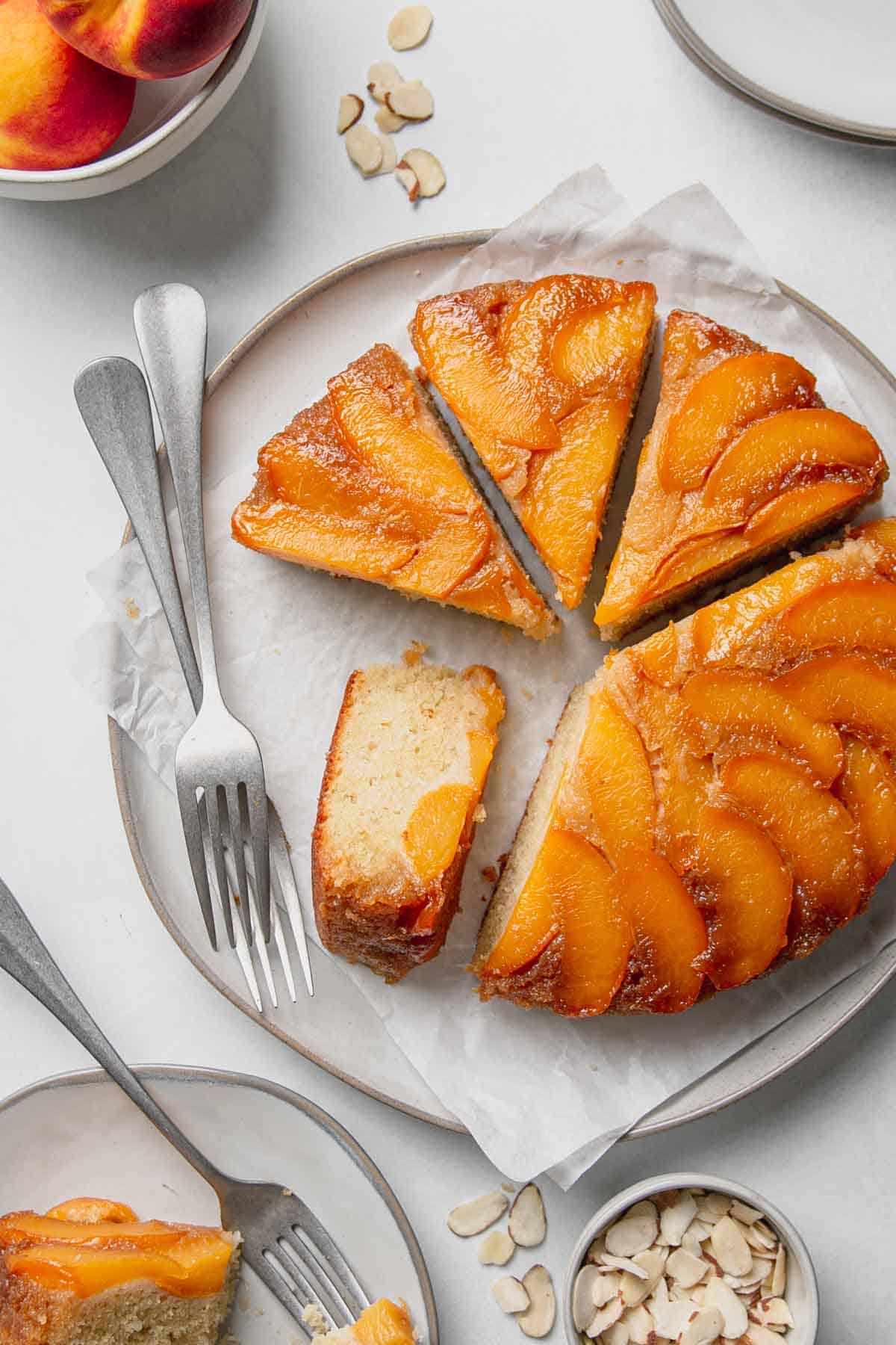 Sliced gluten free upside down cake on a large plate with forks. One slice on its side.