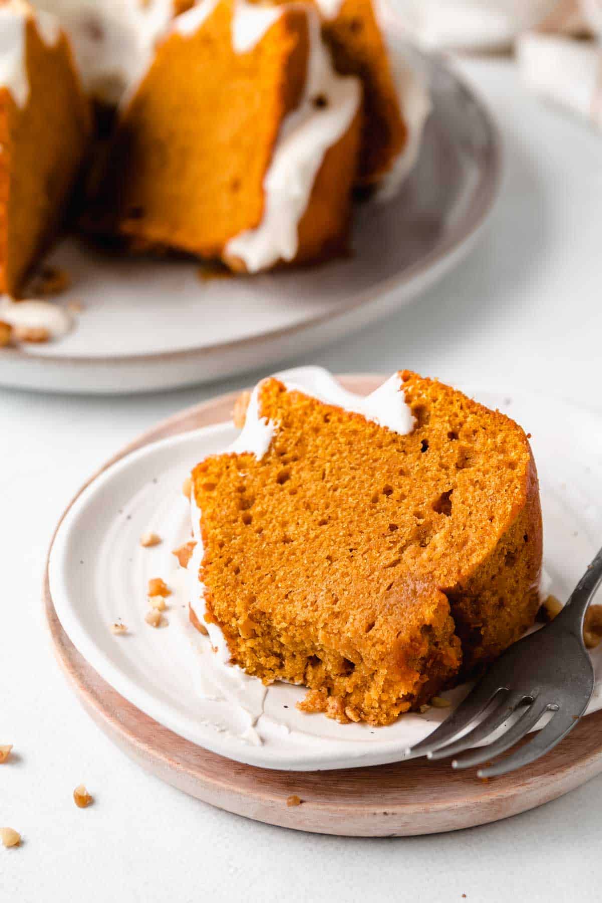 A slice of gluten-free pumpkin cake on a pumpkin shaped plate, with bite removed, next to a fork. 