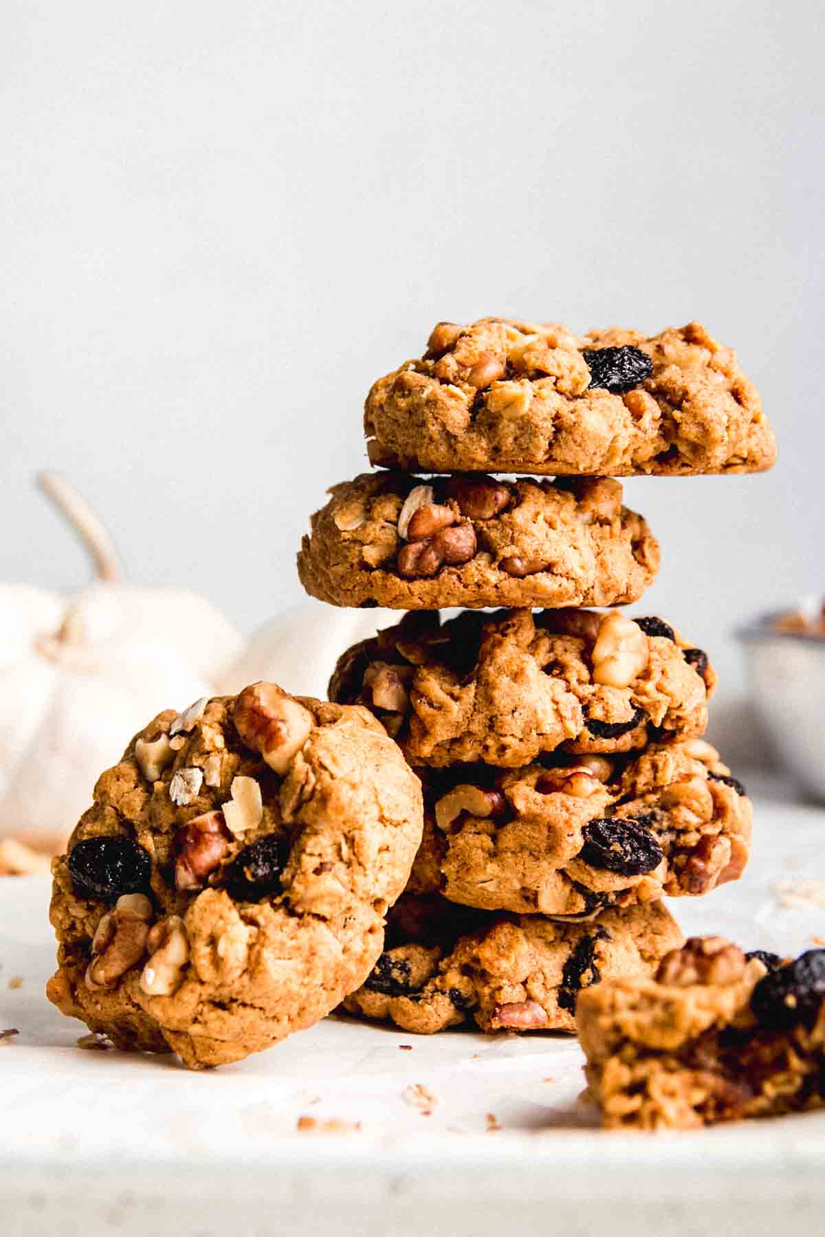 A stack of gluten free pumpkin oatmeal cookies with one cookie leaning on the side of the stack.